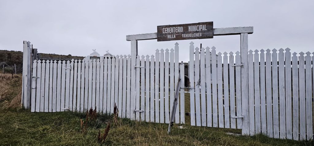 Fachada exterior del Cementerio Municipal Laguna Blanca, destacada por un gran arco de entrada construido con troncos de madera rústica y un cartel central.